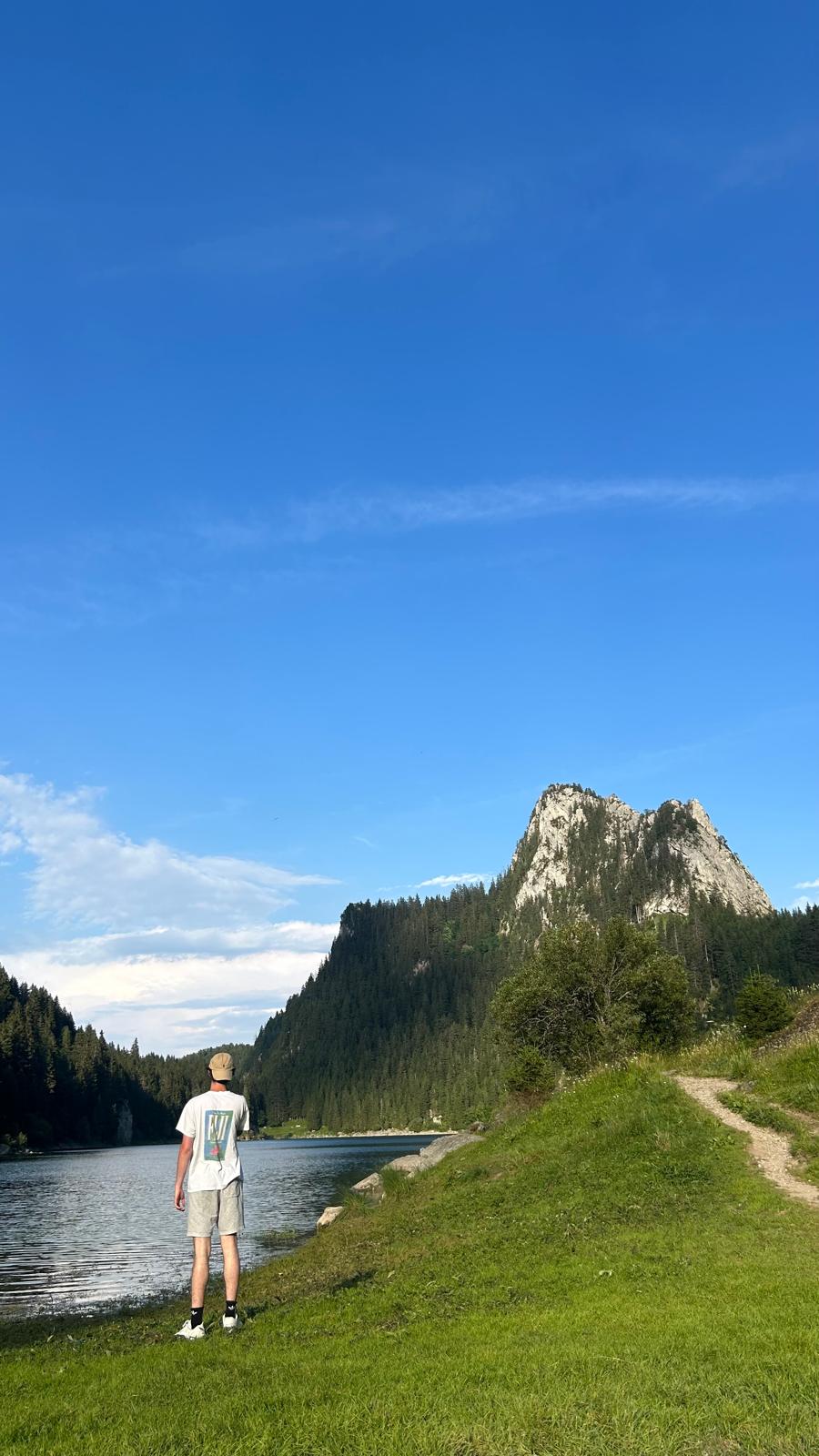 Standing by a lake beneath a mountain peak